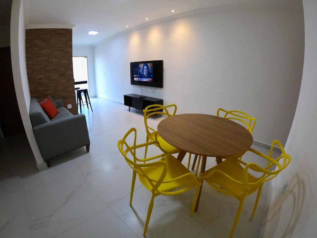 uma sala de jantar com uma mesa e cadeiras amarelas em TH Flats GV Shopping 301 em Governador Valadares