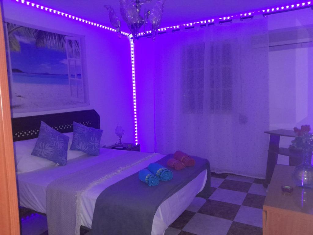 Habitación púrpura con 2 camas y ventana con luces. en Disfruta de un barrio tranquilo, en Alcalá de Guadaira