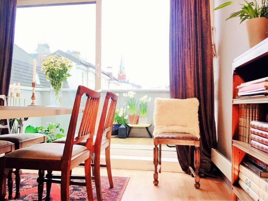 Una sala de estar con una mesa y sillas y una ventana. en Central 2BR with balconies and art in historical university area, en Bergen