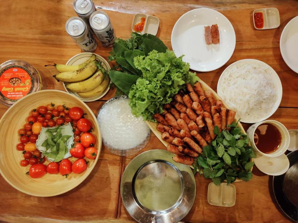 a wooden table topped with plates of vegetables and fruit at Lagom Village (Glamping Site) in Hanoi