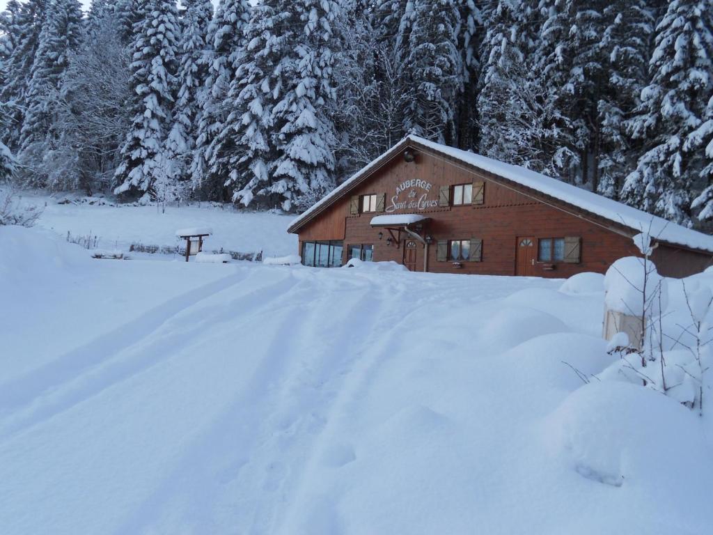 een huis bedekt met sneeuw voor de bomen bij Auberge du Saut des Cuves in Xonrupt-Longemer