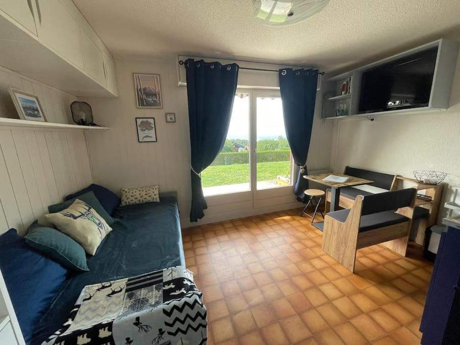 a living room with a couch and a table and a window at Studio Myrtilles du Léman vue sur lac et montagne in Thollon