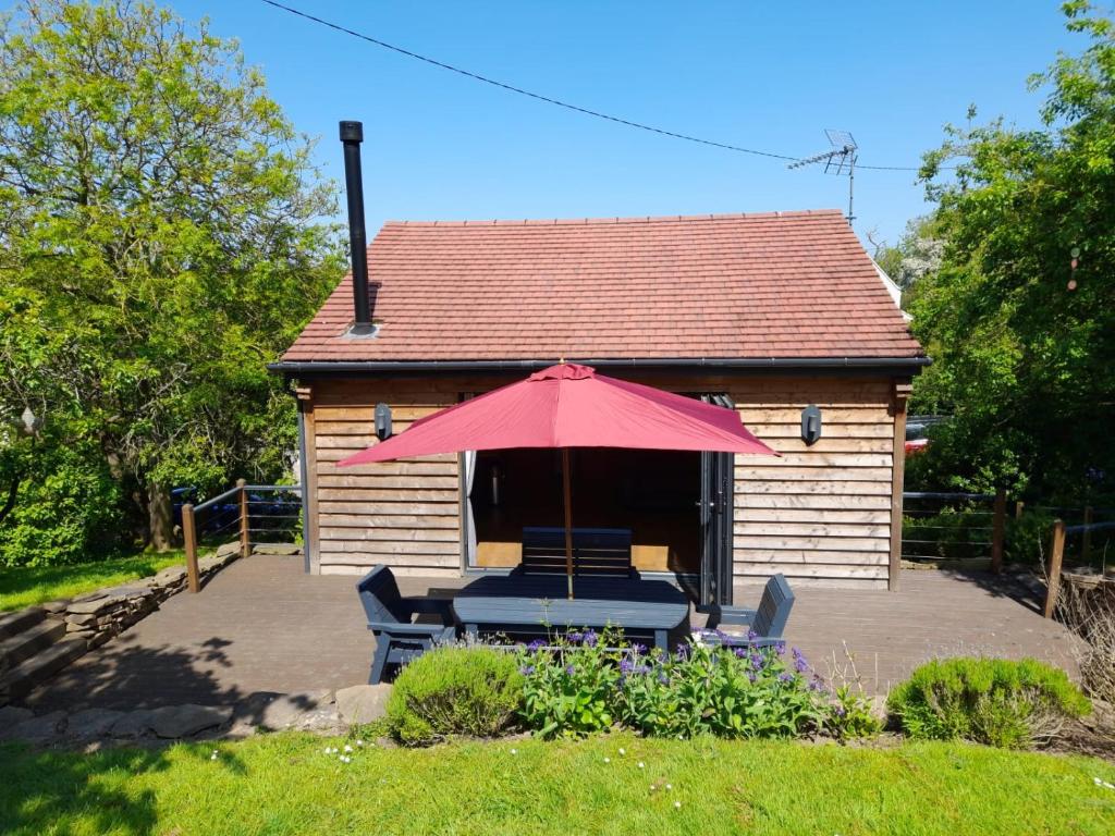 ein Haus mit einem Tisch, Stühlen und einem Sonnenschirm in der Unterkunft Tanners Lodge in Bewdley