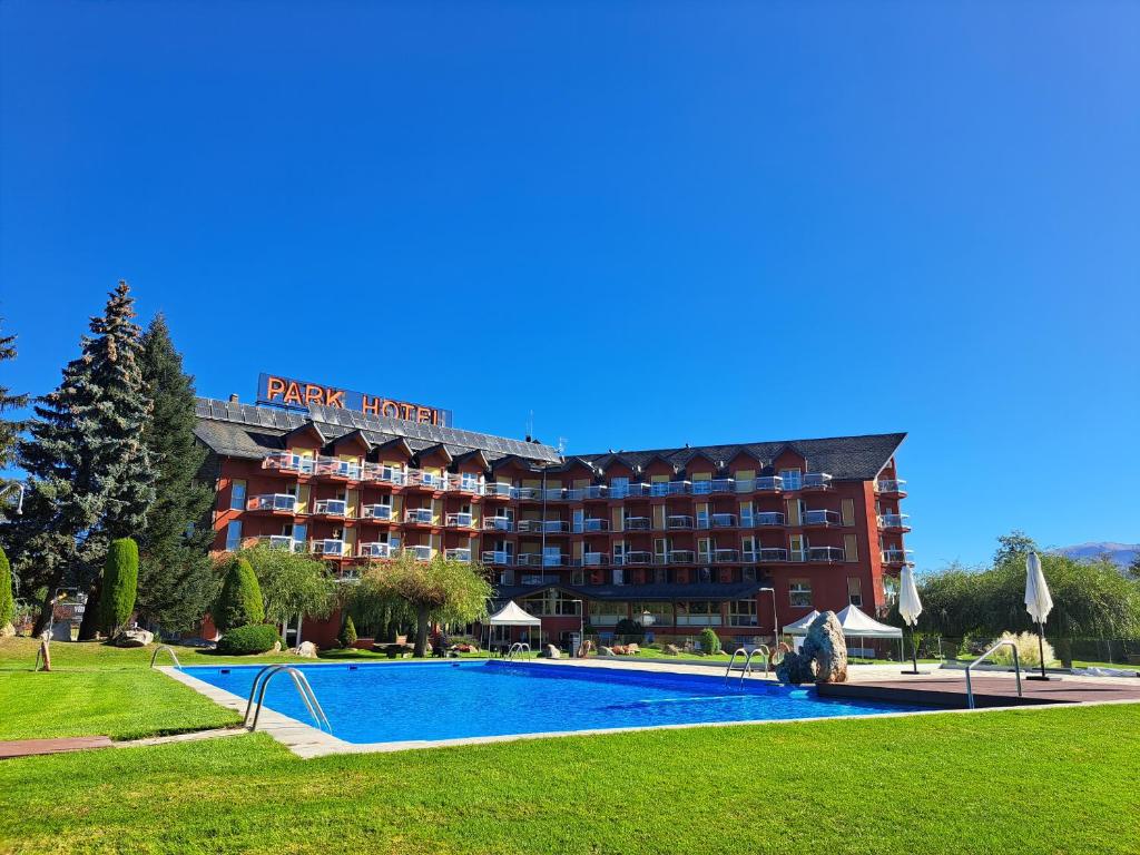um hotel com piscina em frente a um edifício em Puigcerda Park Hotel em Puigcerdà