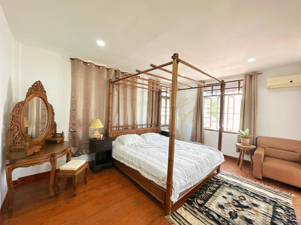 a bedroom with a canopy bed and a table and a couch at An‘s Home in Chiang Mai