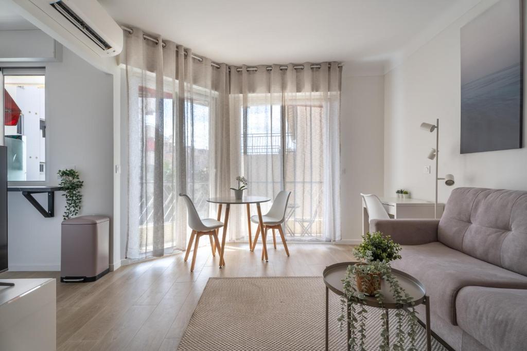 a living room with a couch and a table and chairs at Studio calme et climatisé au cœur de Cannes in Cannes