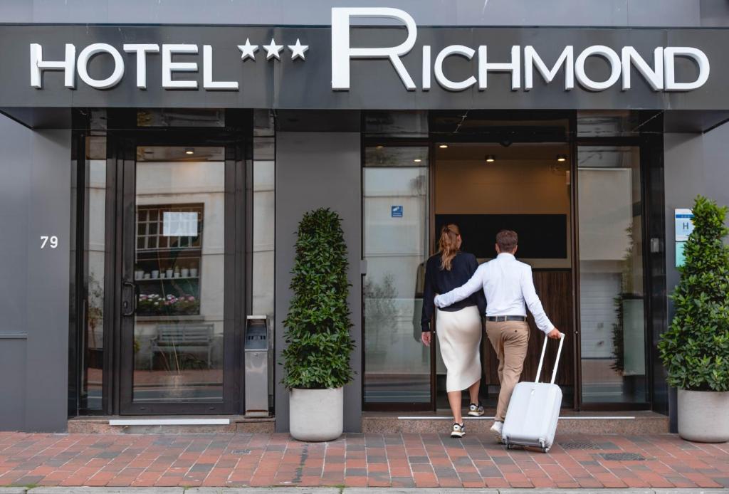 un hombre y una mujer caminando delante de un hotel en Hotel Richmond, en Blankenberge