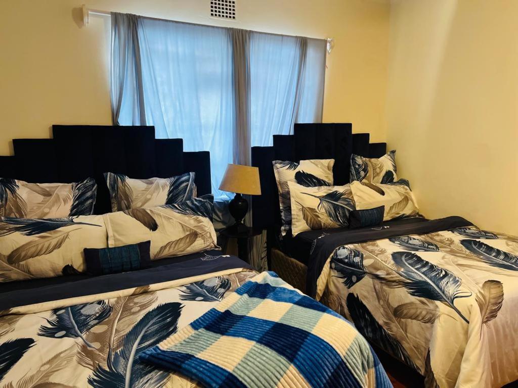 1 dormitorio con 2 camas y ventana en Husein Accommodations en Ciudad del Cabo
