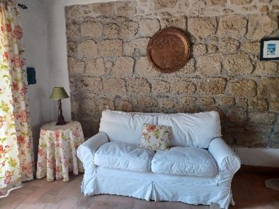 un divano bianco in una stanza con un muro di mattoni di Alloggio turistico Il Villino in Maremma a Farnese
