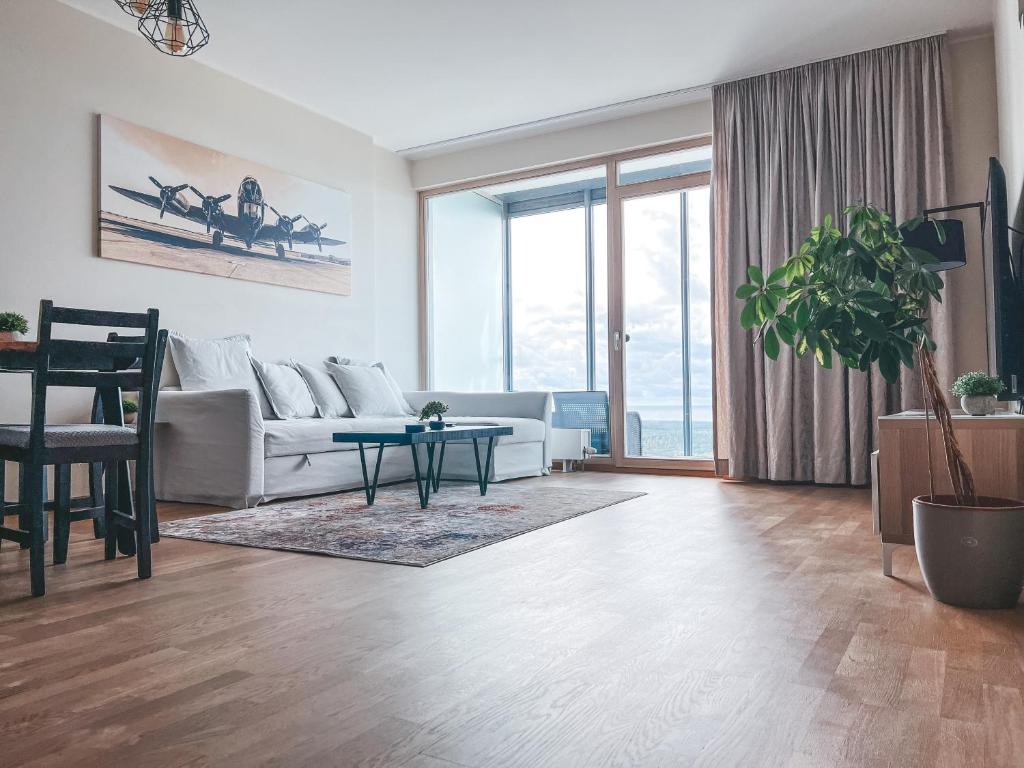 a living room with a white couch and a table at UP 34 FLOOR APARTMENTS in Klaipėda