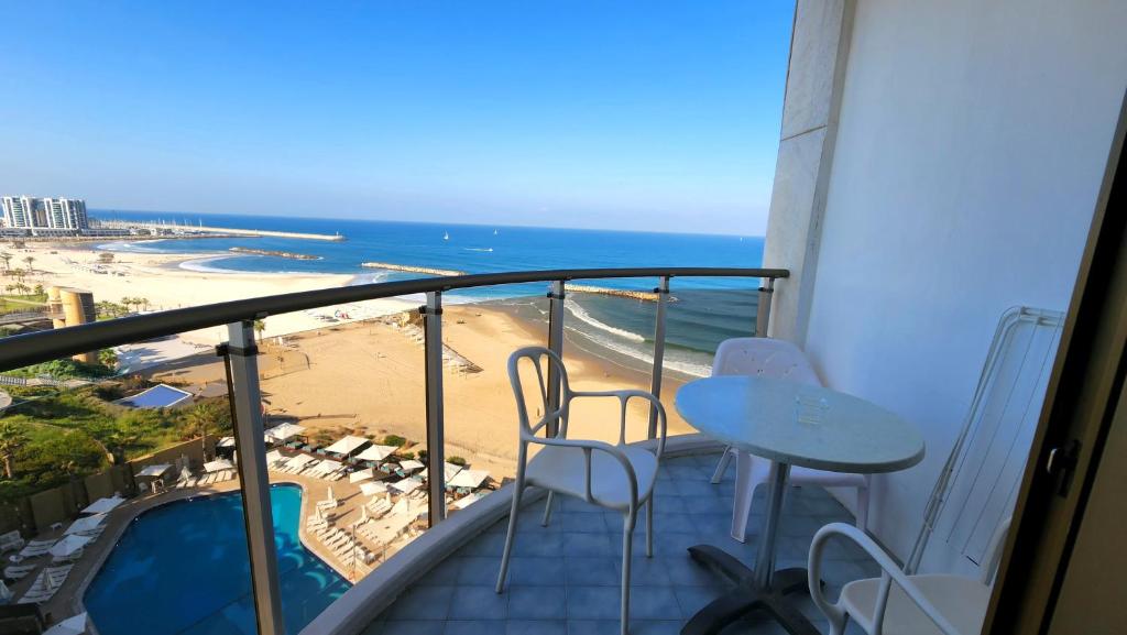 a balcony with a table and chairs and a beach at Herzliya Sea View Hotel Apartment in Herzliya