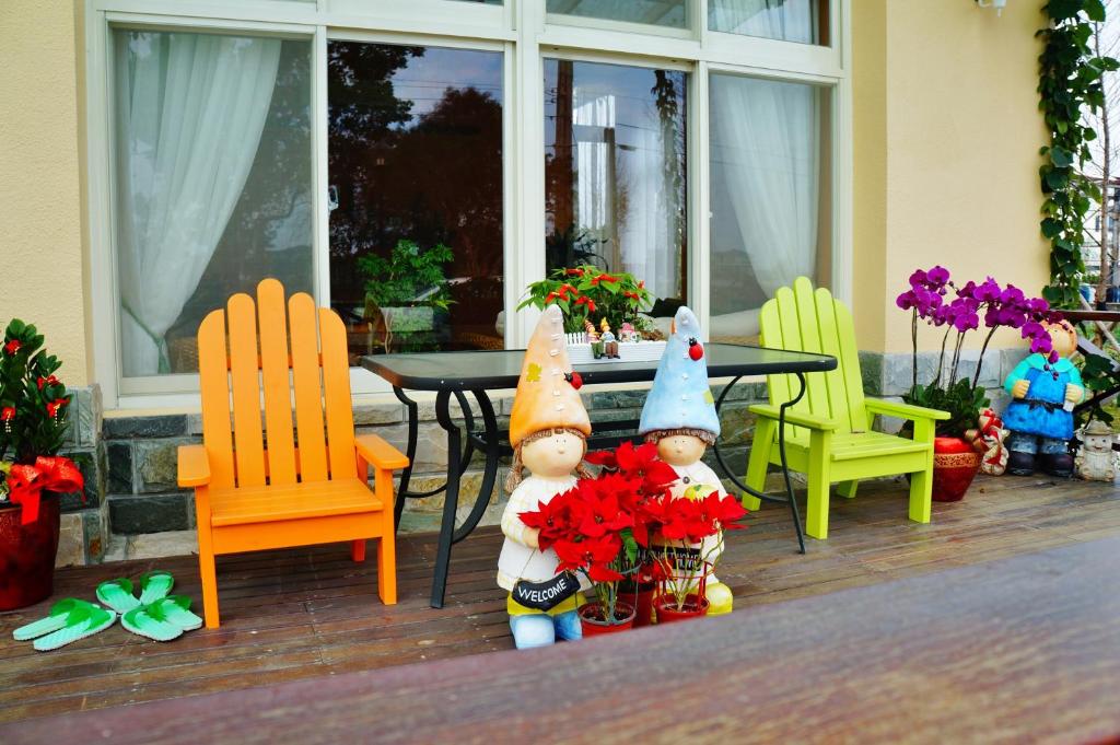 two gnomes sitting on a porch with chairs and a table at Annongriver B&amp;B in Sanxing