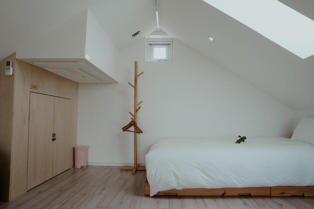 a bedroom with a bed and a white wall at Dalthor Pension in Jeju