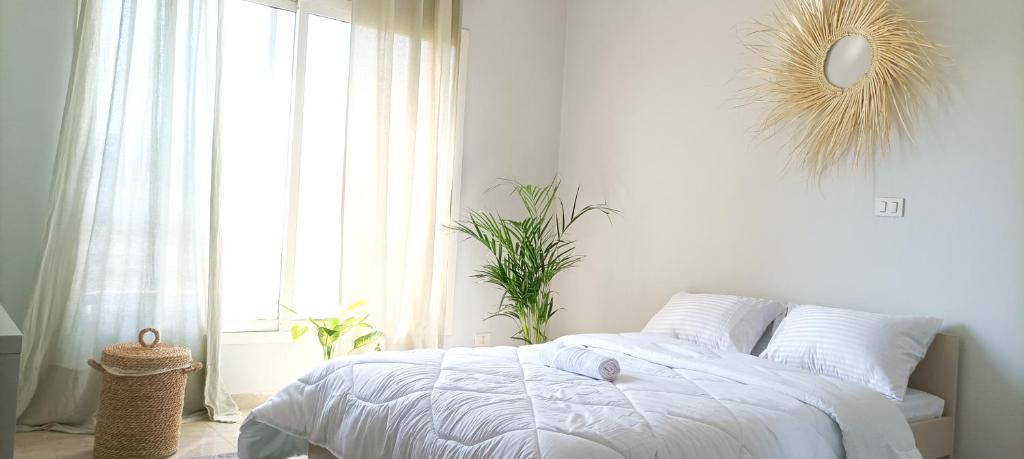 a white bedroom with a bed and a window at white Bear in Madinaty