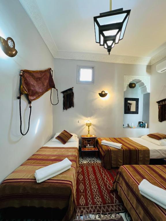 a hotel room with three beds and a chandelier at Riad Al Nour in Marrakech