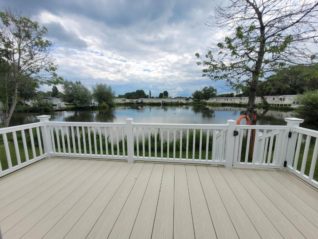 a white wooden deck with a view of a lake at Flamingo Lodge - Mallard Lake in South Cerney