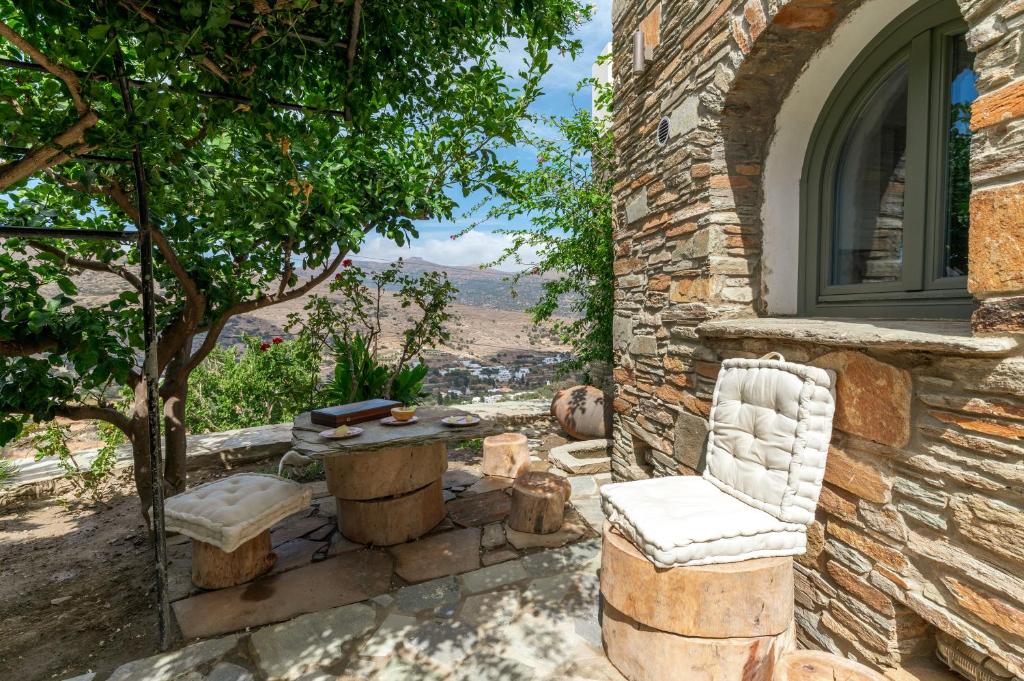 ein Steinhaus mit einem Tisch und einem Stuhl in der Unterkunft Mrs Kalis cottage in Ándros