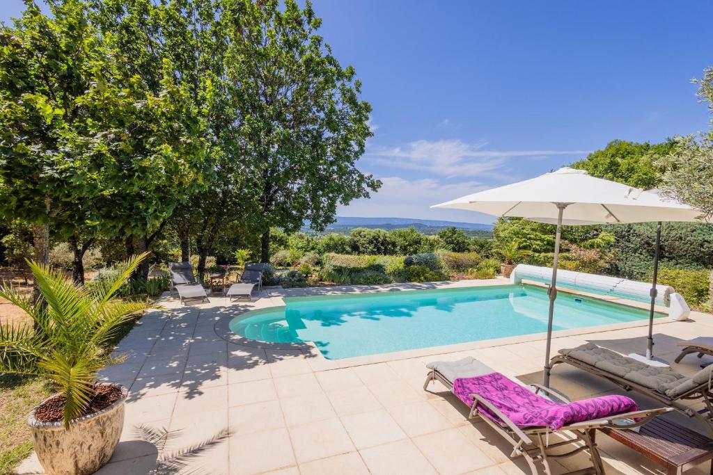 a swimming pool with chairs and an umbrella next to a pool at Gîte L'Escapade in Saint-Saturnin-dʼApt