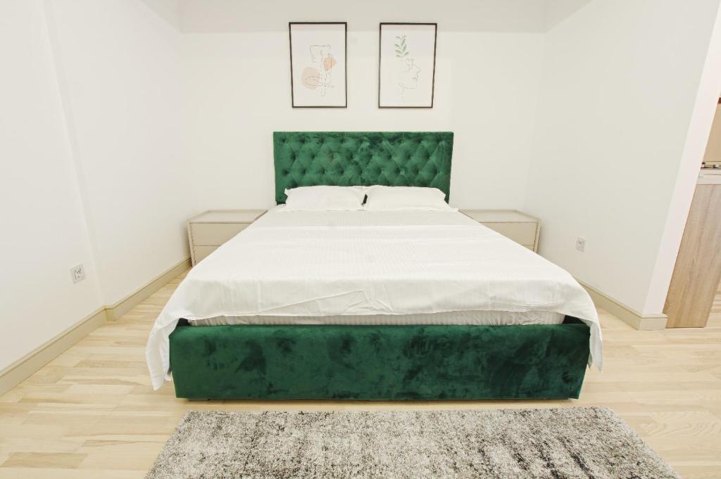 - un lit dans une chambre blanche avec une tête de lit verte dans l'établissement Himson-Green Apartment, à Iaşi