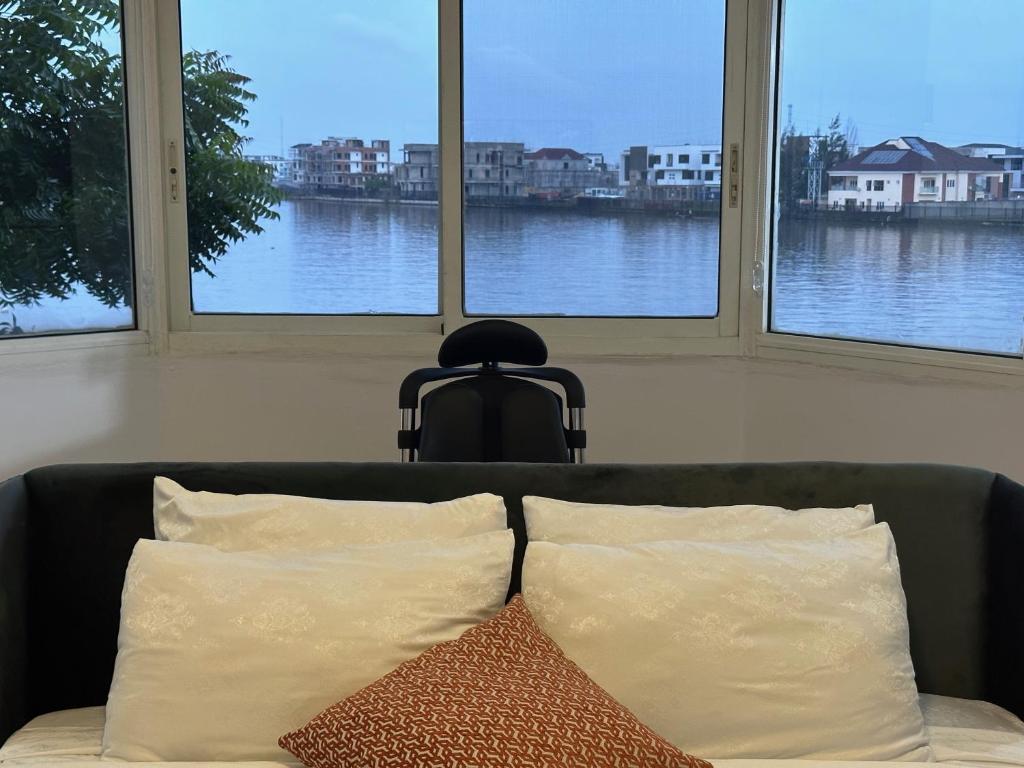 - un canapé avec deux oreillers devant trois fenêtres dans l'établissement Guided Hospitality - Luxury Accommodations, à Lagos