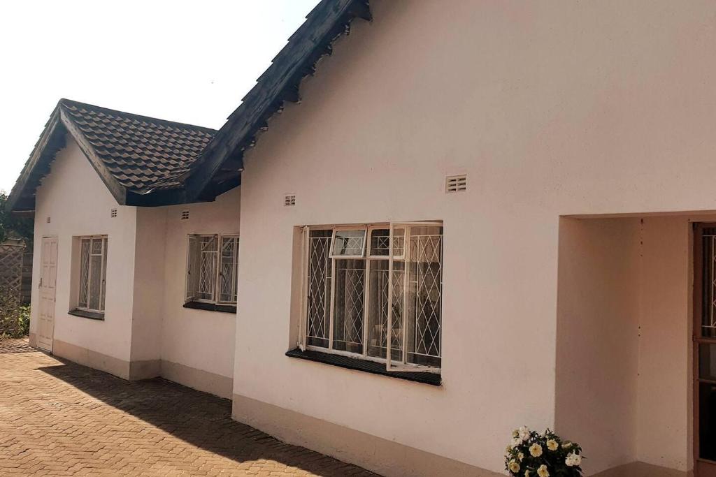 a white house with windows on the side of it at Stunning 3-Bed House in Harare in Harare