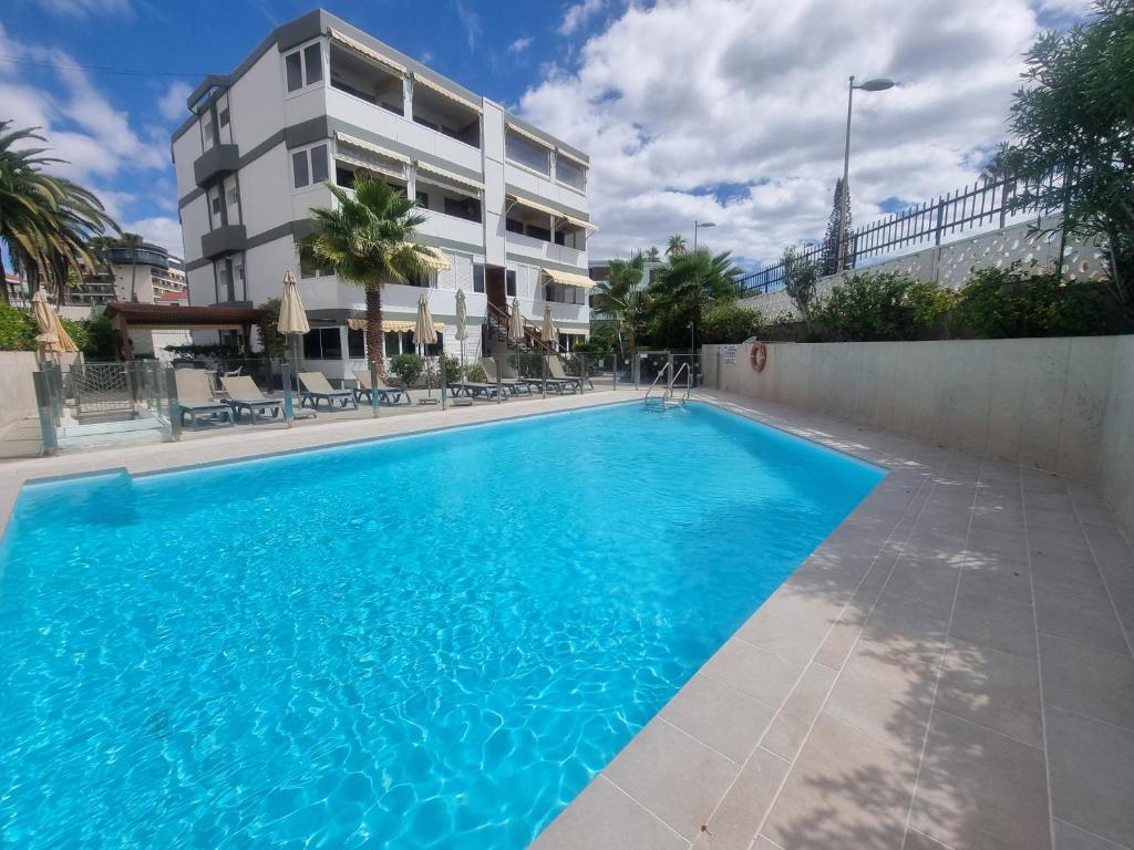 a large blue swimming pool in front of a building at Apartamento en Playa del Inglés Los Mangos in Playa del Ingles