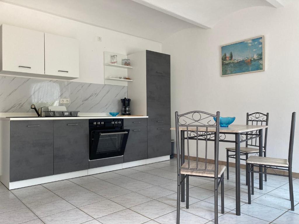 a kitchen with gray cabinets and a table and chairs at Gästehaus Lauerwald in Niesky