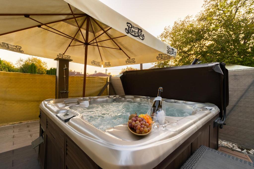 a hot tub with a bowl of fruit and an umbrella at Szelidi Apartmanok in Dunapataj