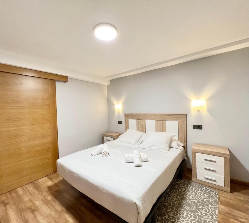 - une chambre avec un lit blanc et une porte en bois dans l'établissement Apartamento San Juan de la Cruz, à Gijón