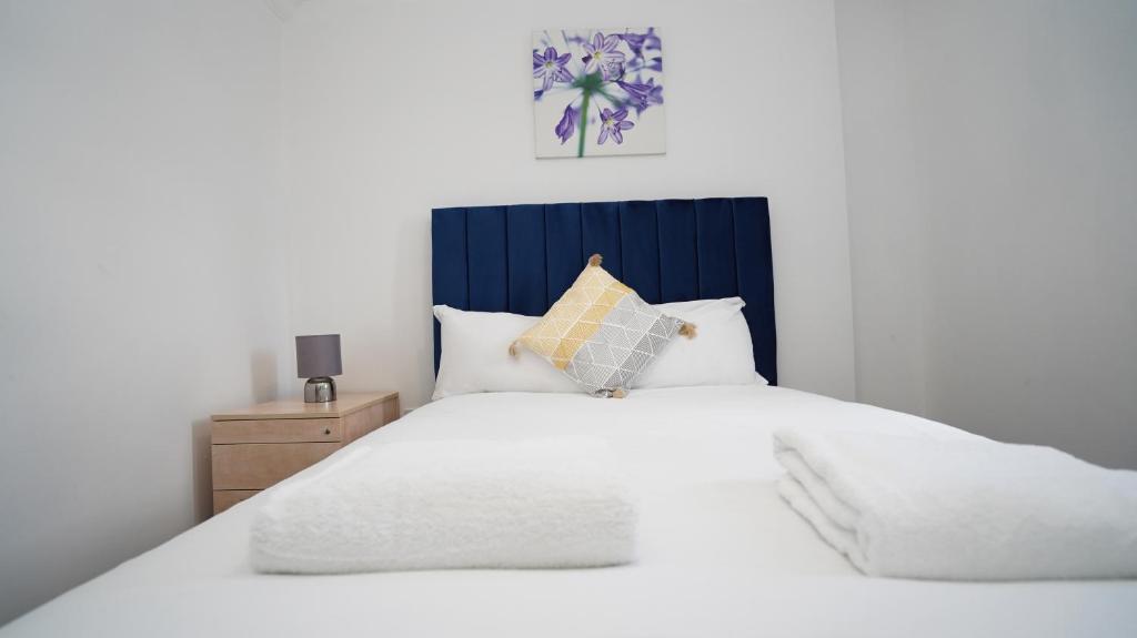 um quarto com uma cama branca e uma cabeceira azul em E2M Stays 3Bed Spacious House Free Parking Close To Heathrow em Farnham Royal