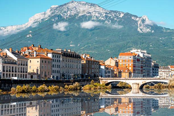 a city with a bridge and buildings and a mountain at Appartement cosy au cœur de Grenoble avec Parking gratuit in Grenoble