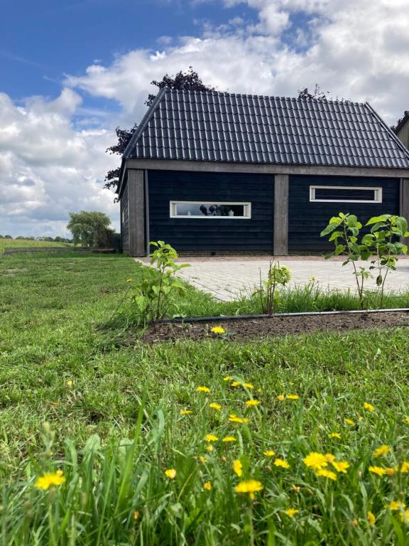 een huis met een zwart dak en een bloemenveld bij De Barg in Vinkenbuurt