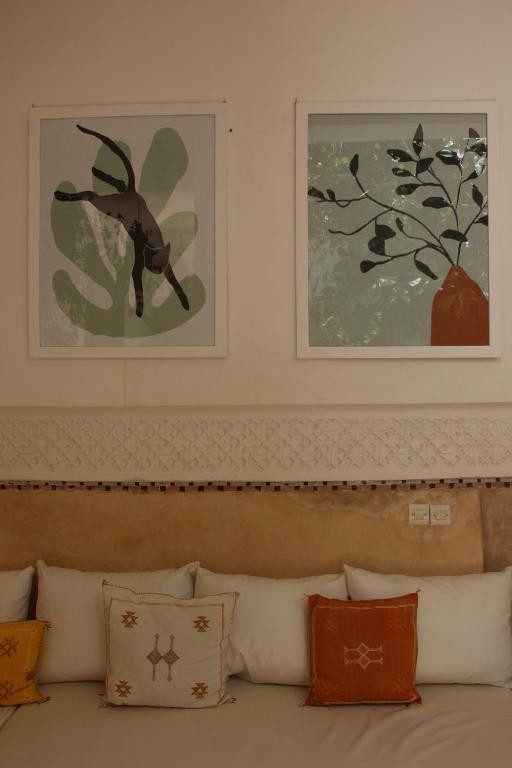 zwei Bilder an der Wand über einer Couch mit Kissen in der Unterkunft Riad Dar Nael in Marrakesch