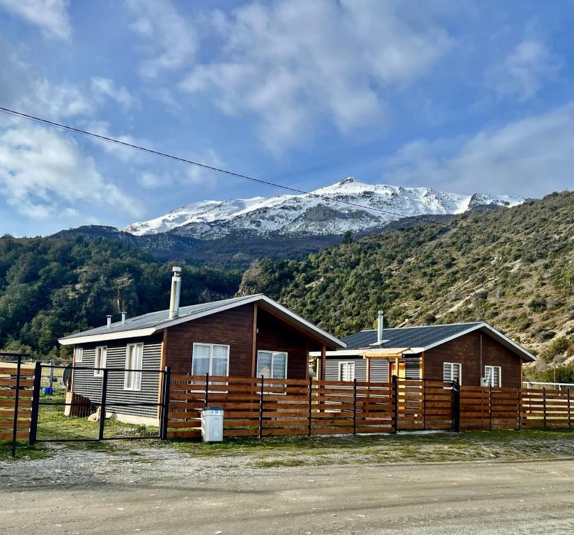 une maison avec une clôture en face d'une montagne dans l'établissement Cabaña Puerto Sánchez RYS Patagonia A, 