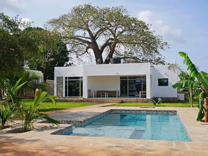 a house with a swimming pool in front of a house at 4 U Luxury Bungalows Diani in Diani Beach