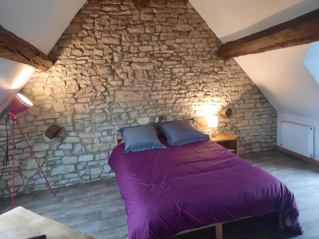 um quarto com uma cama roxa numa parede de pedra em Maison de ville em Déols
