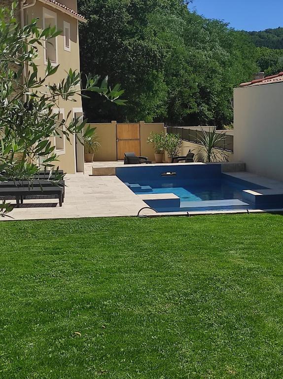 a swimming pool in a yard with green grass at Apparts'hôtel la ferme du gros noyer in Malaucène