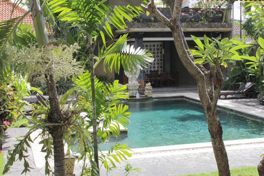 a pool in the middle of a garden with trees at Mangga Bali Inn in Legian