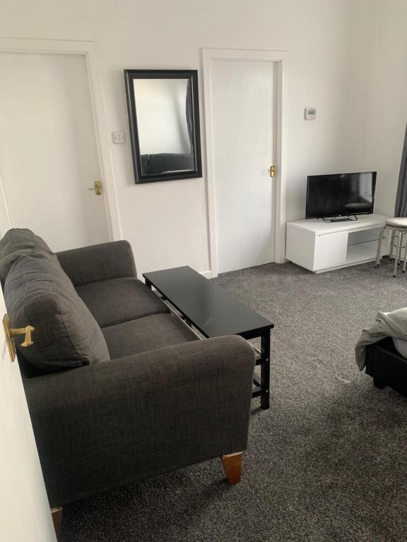 ein Wohnzimmer mit einem Sofa und einem TV in der Unterkunft New 2 bedroom Apartment in Greater Manchester in Ashton under Lyne
