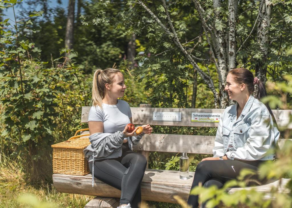 zwei Frauen auf einer Bank im Park in der Unterkunft Hotel Saigerhöh Wellness Spa Golf Wandern über dem Titisee in Lenzkirch