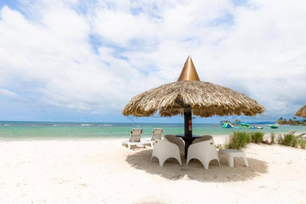 a beach with chairs and an umbrella and the ocean at Villa Cala Marina + Jacuzzi in Colón