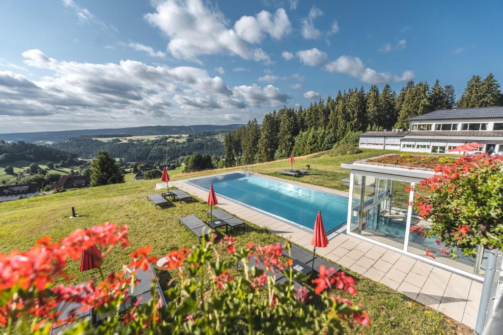 una casa con piscina su una collina con fiori di Hotel Saigerhöh a Lenzkirch