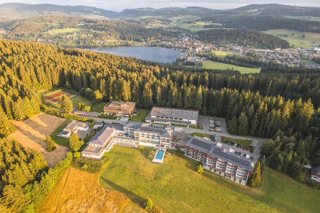 eine Luftansicht eines Gebäudes auf einem Hügel mit einem See in der Unterkunft Hotel Saigerhöh Wellness Spa Golf Wandern über dem Titisee in Lenzkirch