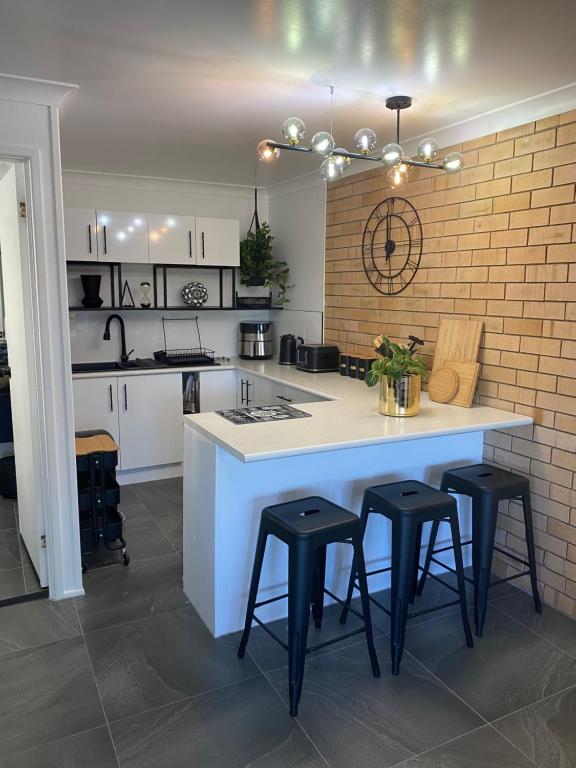 a kitchen with a white counter and black stools at Beach House in Yeppoon