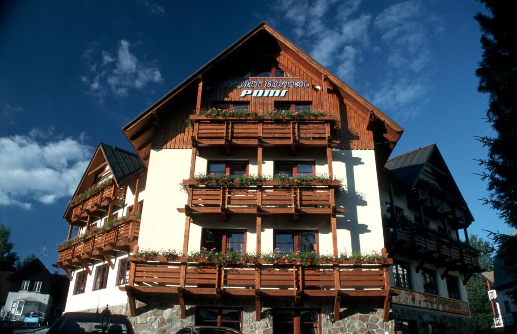 un edificio de madera con flores. en Sport hotel POMI, en Harrachov