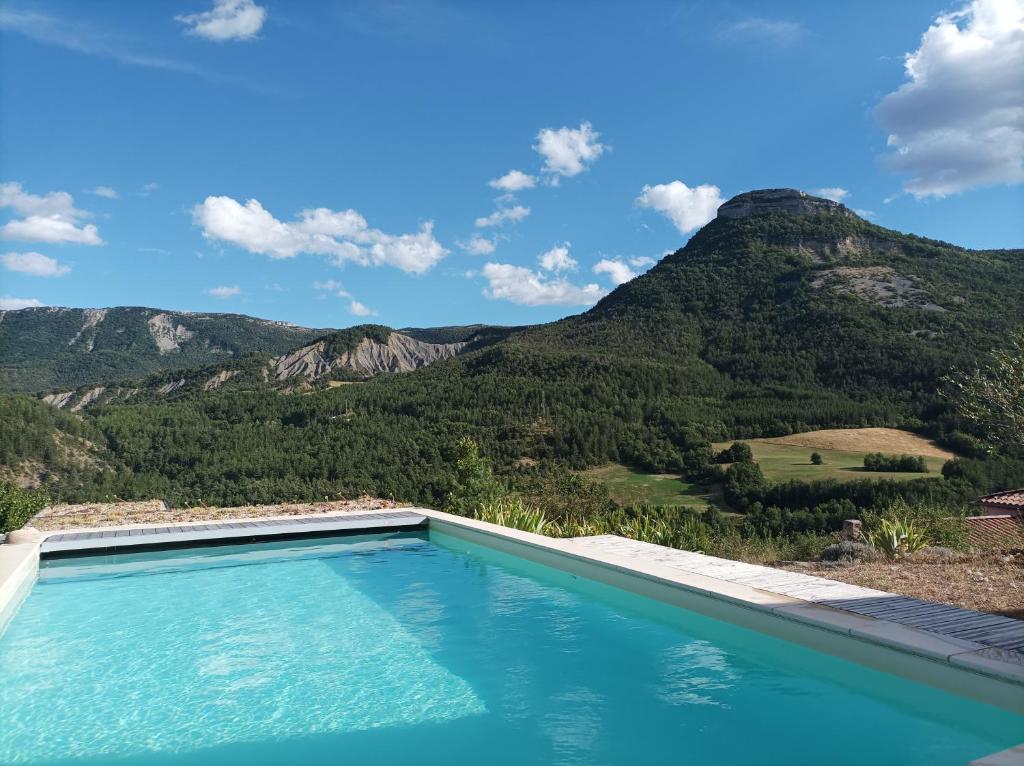 a swimming pool with mountains in the background at Un petit coin de paradis in Orpierre
