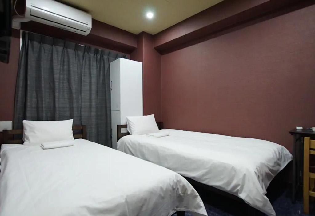 - 2 lits dans une chambre aux murs rouges dans l'établissement TOKYOGUEST日本橋, à Tokyo