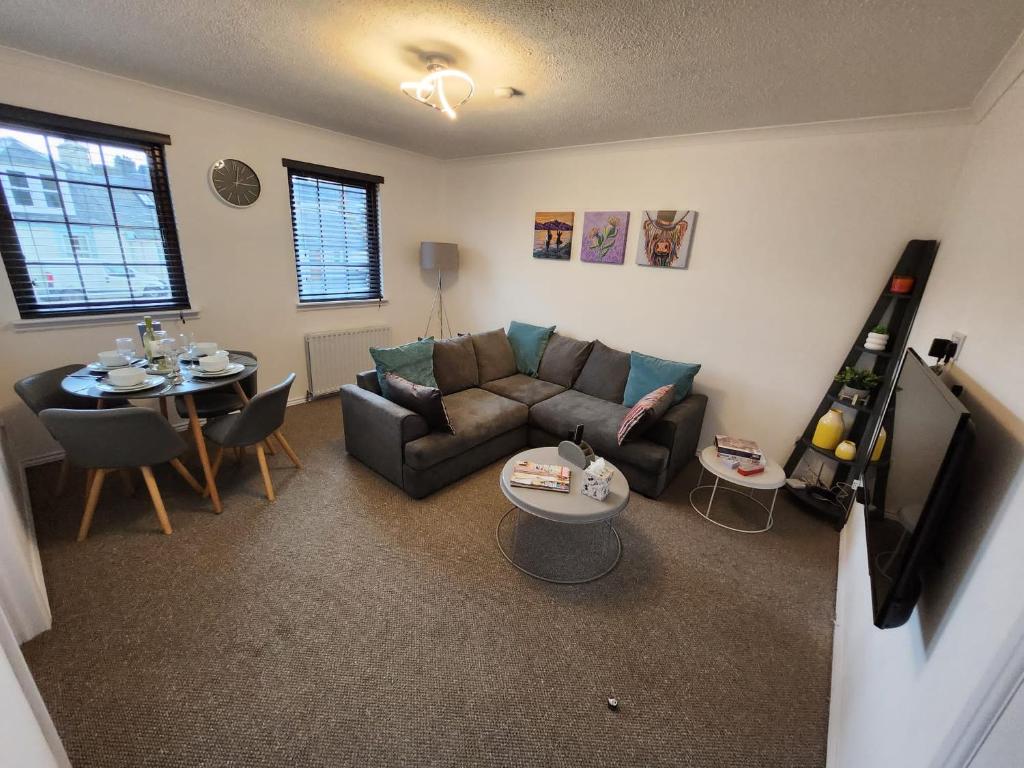 ein Wohnzimmer mit einem Sofa und einem Tisch in der Unterkunft 10 Ladyknowe court in Moffat