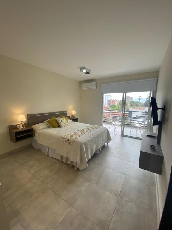 a bedroom with a large bed and a balcony at Apart Moderno a Estrenar Barrio Sur in San Miguel de Tucumán
