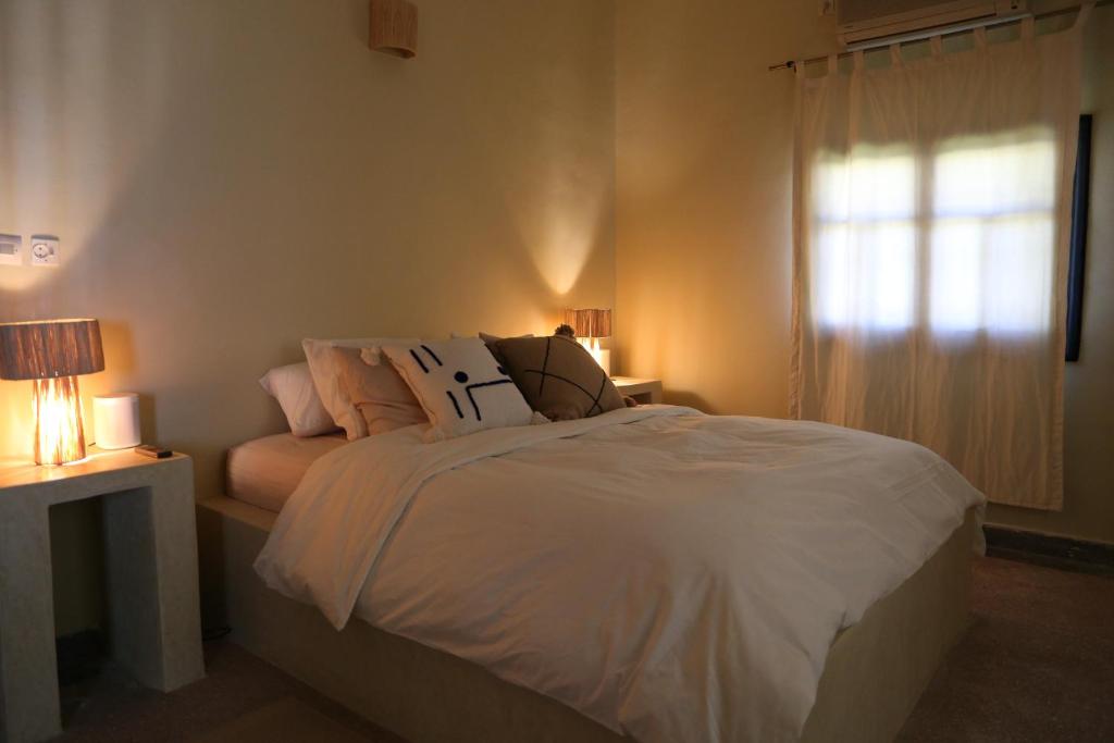 a bedroom with a white bed and a window at Kasbah des cyprès in Skoura